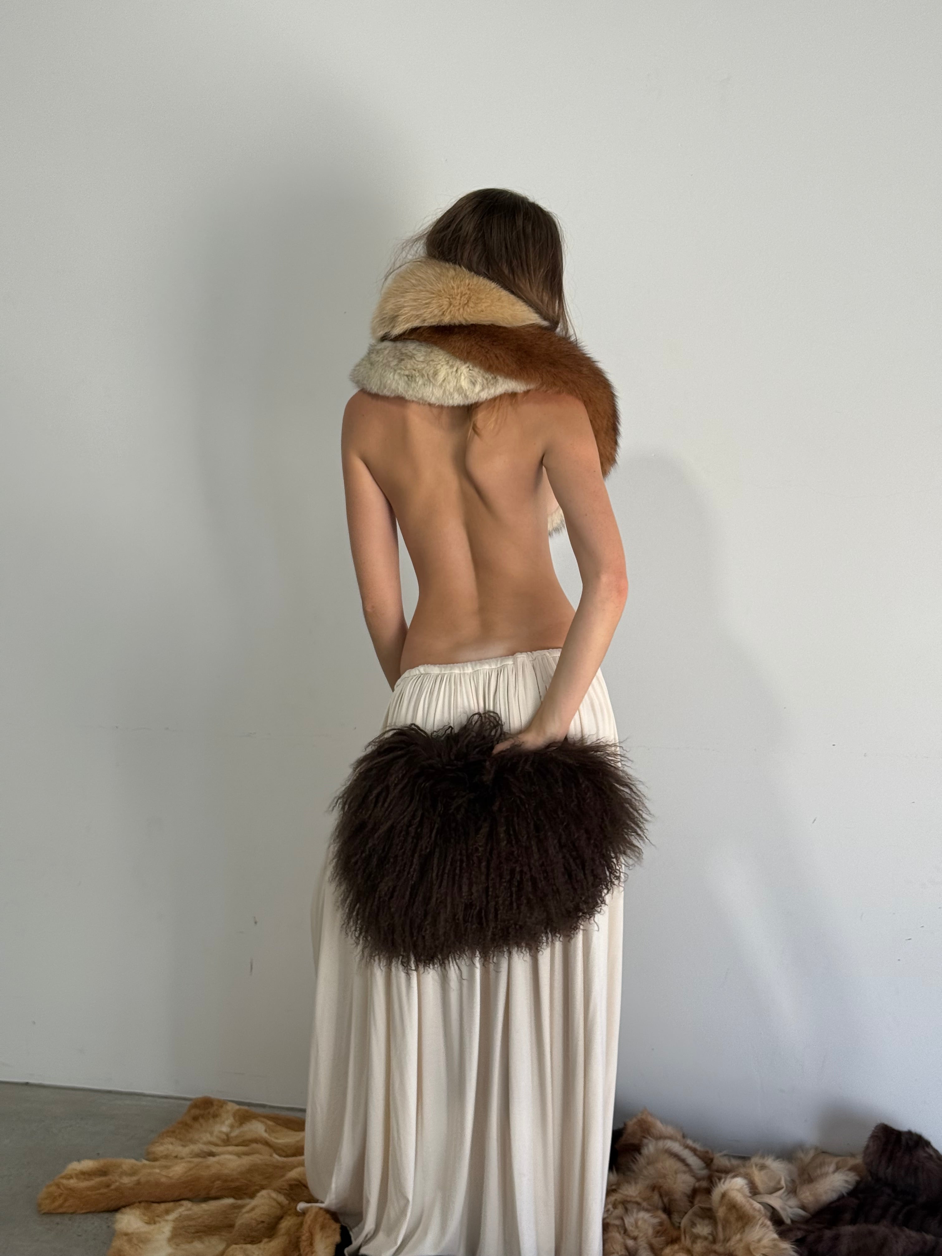 Mannequin wearing a white dress with fur accents on a plain background