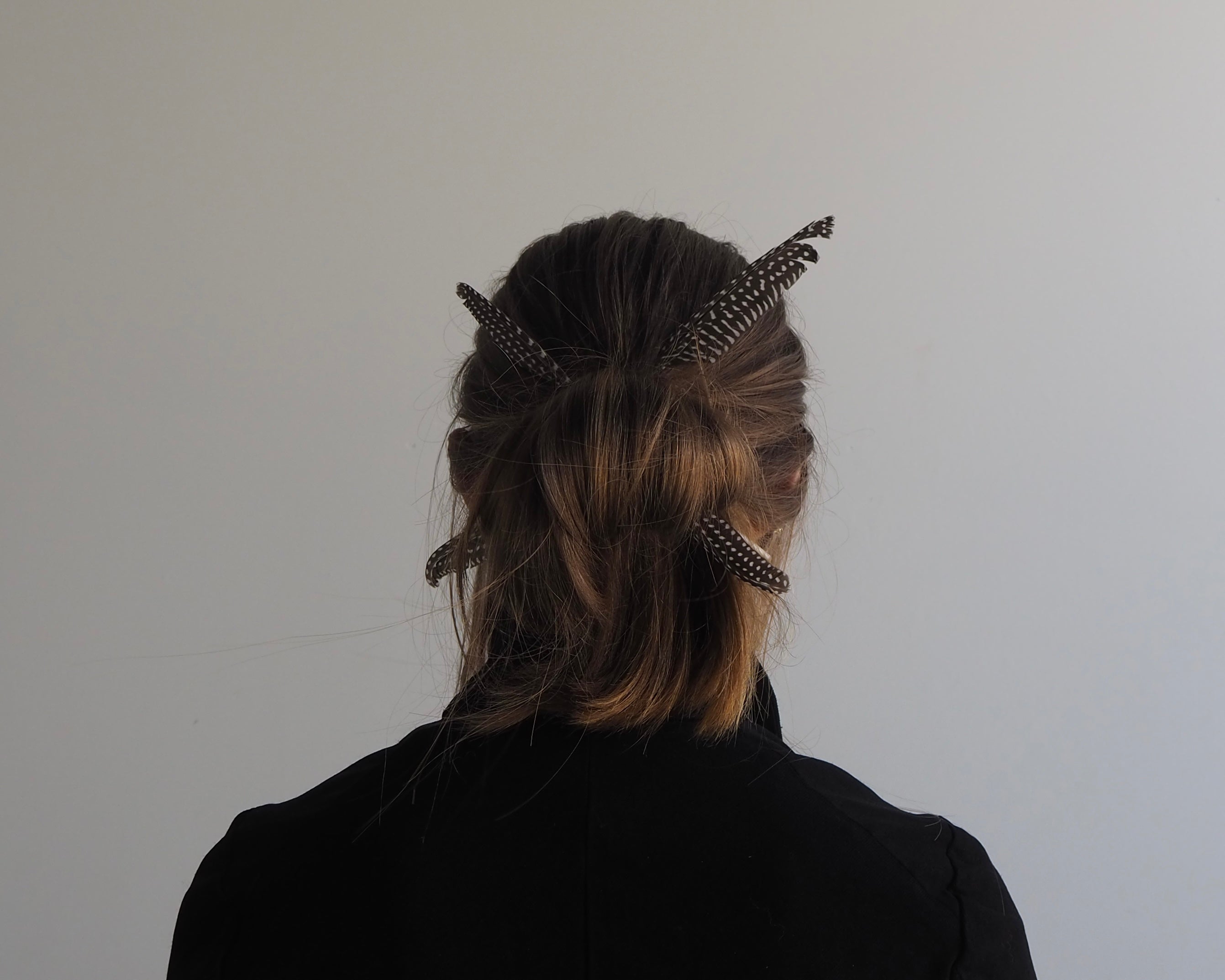 Person with decorative hairpins in their hair against a plain background