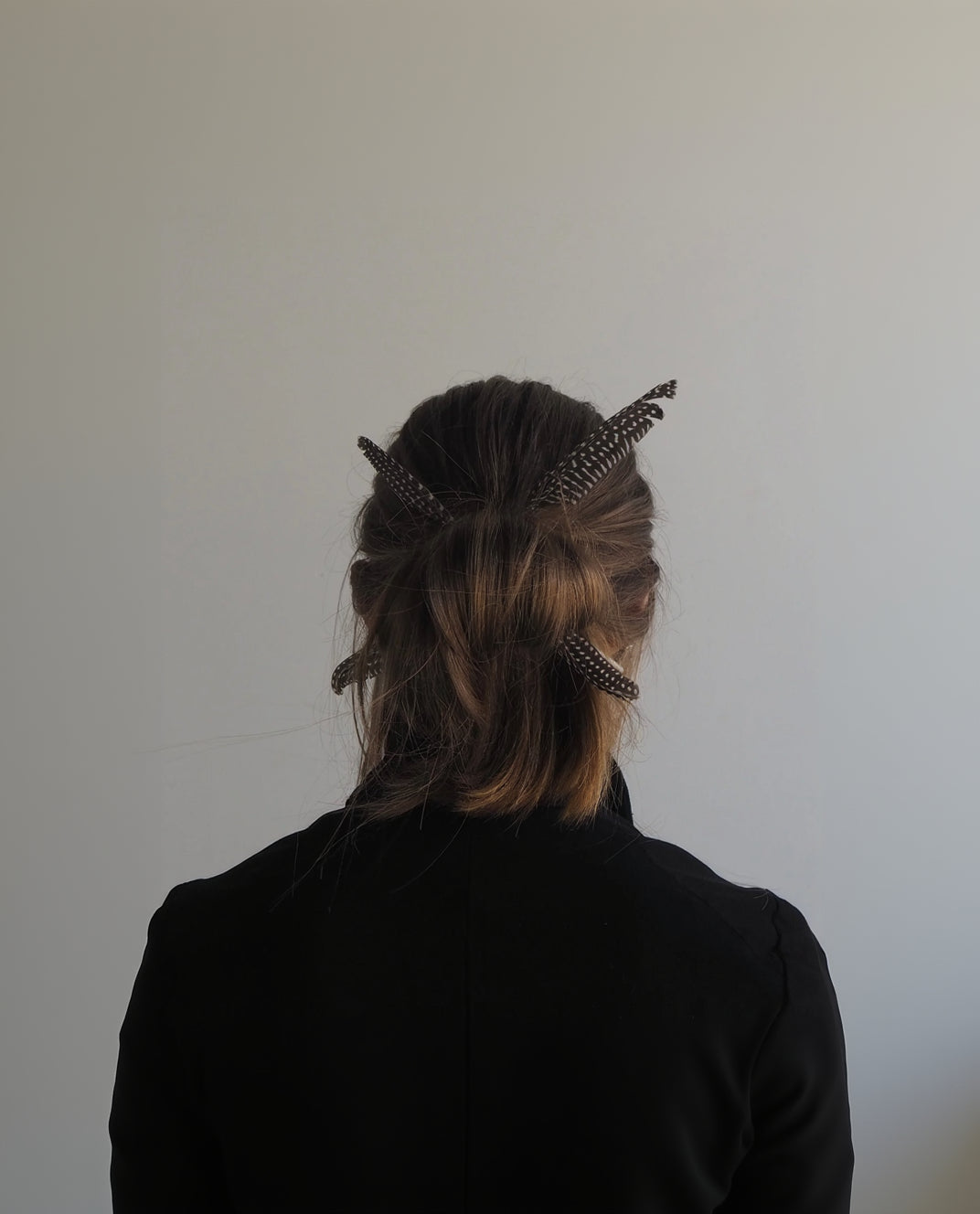 Person with decorative hairpins in their hair against a plain background